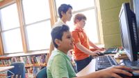 three boys looking at computers