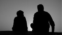 Photo of adult and child sitting side by side