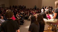 Room filled with people listening to a group at the front