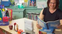 Teacher sitting at her desk reading from a student composition book