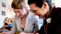Two women at desk looking at papers together