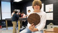 Boy holding slice of tree showing age rings