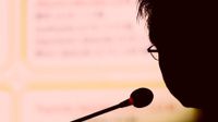 Silhouette of a person speaking while looking at data projected on a screen