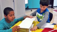 Two boys working with paper and scissors