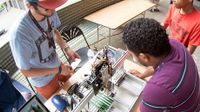 Man and boy visiting a work station with laptop and circuit boards