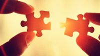 Hands holding two puzzle pieces