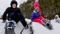 Four students wearing snow shoes sitting on a mound of snow