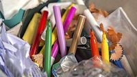 A photo of a classroom garbage can, with wadded up papers, pencils, and markers.