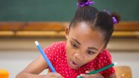 Young girl concentrating on writing with pencils in each hand