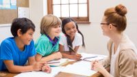 A teacher talks to three young students.