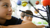 A photo of an elementary-school girl looking at a model of the solar system.