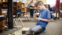 A boy works on the floor in his class.