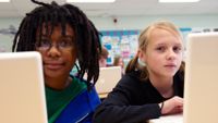 Two kids sitting side-by-side with their laptops