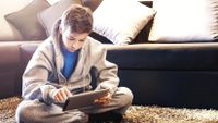 A boy does schoolwork on an iPad on a snow day.