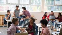 Small groups of students work on different tasks in a classroom.