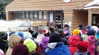 A photo of elementary school children listening to a naturalist at the zoo.