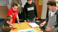 Students gathered around a table playing a board game