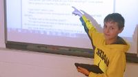 Boy standing in front of class pointing at screen