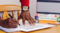 Close up of man's hands on desk with papers and books