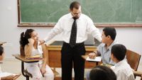 Students sit in a circle to mediate a difference as a teacher looks on.