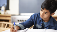 A photo of an elementary-school boy writing in his notebook.