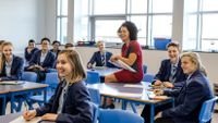 A teacher sits with her students in the classroom.