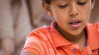Close-up shot of a boy in an orange shirt