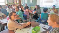 A classroom filled with teachers talking to each other while seated