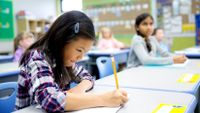 A young Asian girl works on her writing in class.