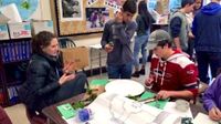 Two boys and a girl around a table working on a project