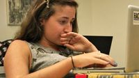 A closeup of a teenage student sitting and working on her laptop.