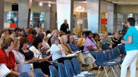 A group of educators are sitting in a room, listening to a speaker.