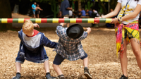 A photo of 2 elementary-school boys going under a limbo bar.