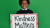 photo of a student holding a sign which reads "Kindness Matters"