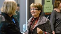 Two teachers are talking to each other out in the hallway.