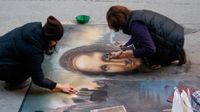 photo of two people completing a detailed chalk drawing