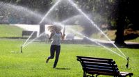 photo of a woman running through the sprinklers