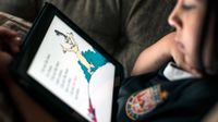 A closeup of a kid sitting, reading Dr. Seuss on a tablet.