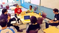 group of teachers sitting in a circle around desks