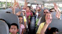 photo of students on a bus with their hands in the air