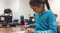 A young girl is sitting in class building a toy car.