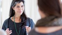 Two female teachers from the waist up, facing each other, talking.