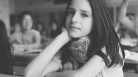 black and white photo of a student at a desk looking at the camera