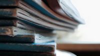 A closeup of a stack of blue, old, faded books on a circular table.