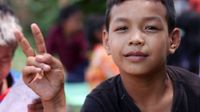 A closeup of a young boy giving the peace sign with his fingers.