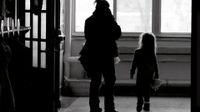 An adult woman and a young girl are walking down a school hallway.