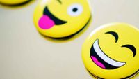Three smiley face icons against an off-white backdrop. One is kissing, one is winking, and one is smiling widely.
