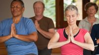 Adults sitting, kneeling on the floor practicing yoga