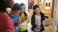 Four girls working as a team in front of a whiteboard