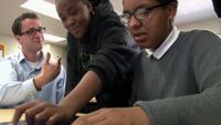 Teacher is talking to his students while they're working.